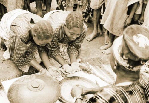 Pagan Babalawo; father in things spiritual and material, divining for two clients in Ile-Ife, 1937